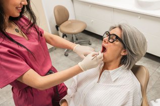 Dentist examining a patient's mouth for a cold sore or canker sore
