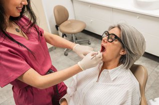 Dentist examining a patient's mouth for a cold sore or canker sore